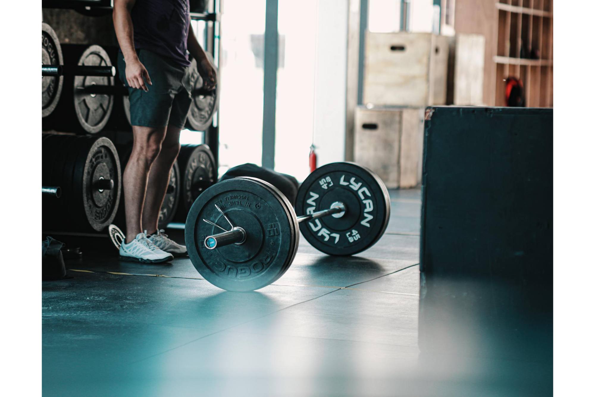 man standing beside a barbell on the floor for a home wellness gym