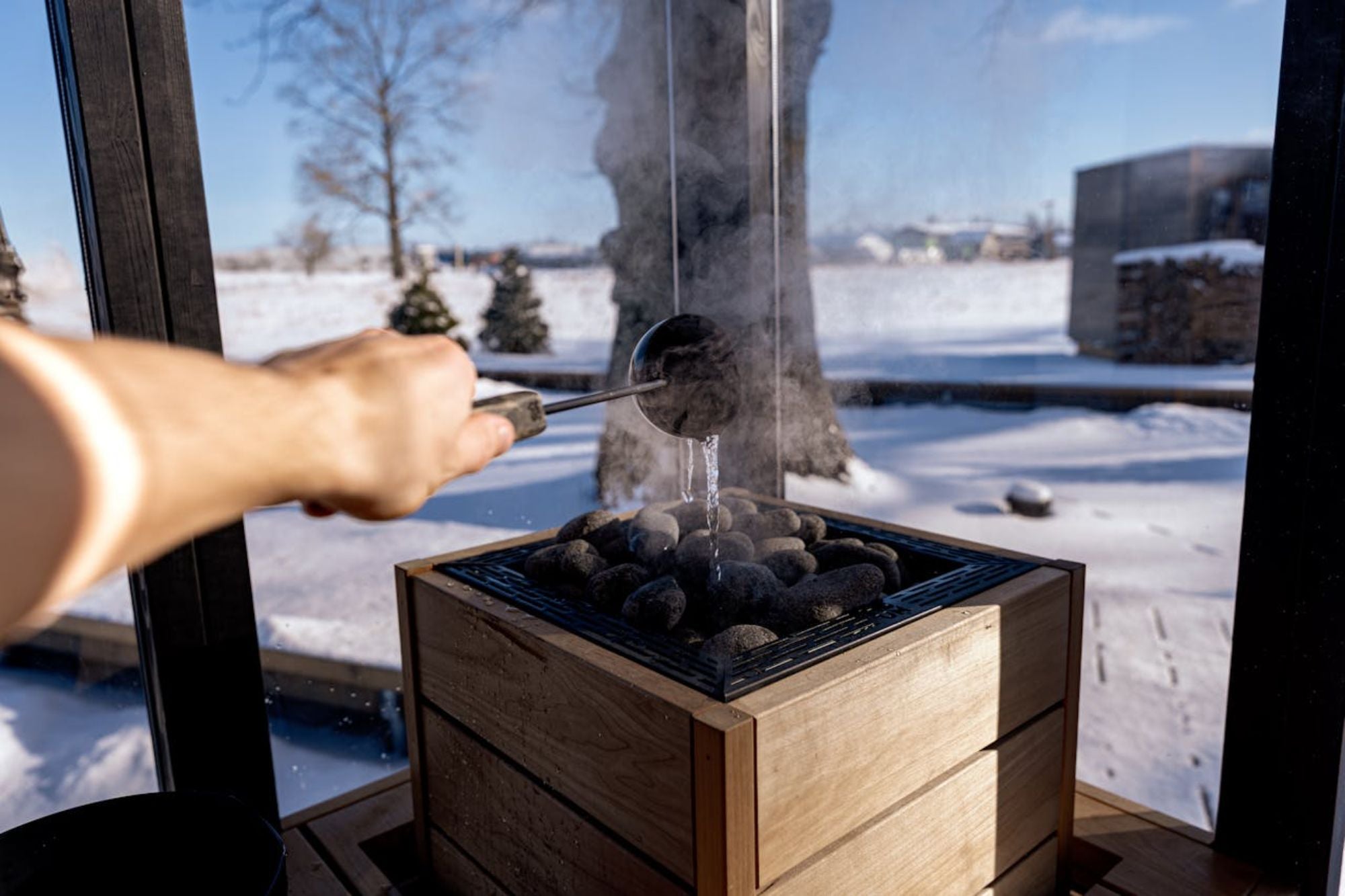 Man pouring water over sauna rocks after he purchased an outdoor sauna for sale