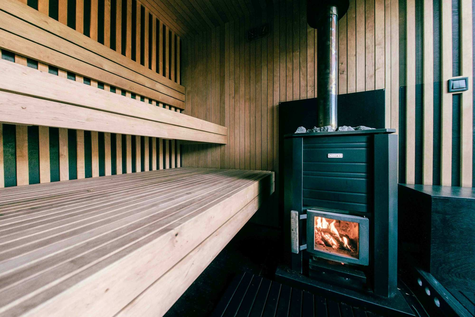 Interior view of a exterior sauna kits showing the wood burning heater and wooden sauna benches