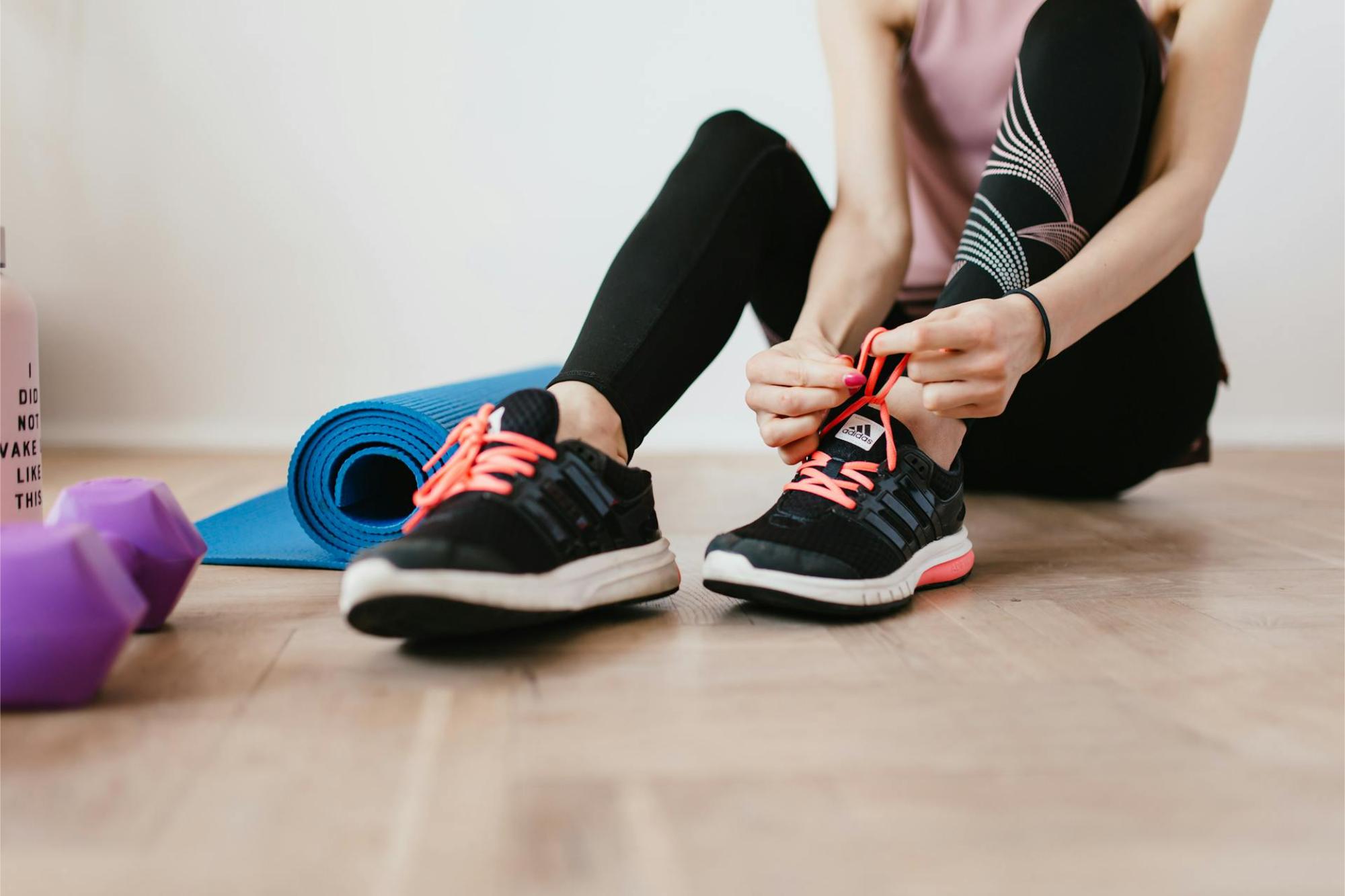 woman sitting down and tying her shoes in a home wellness space