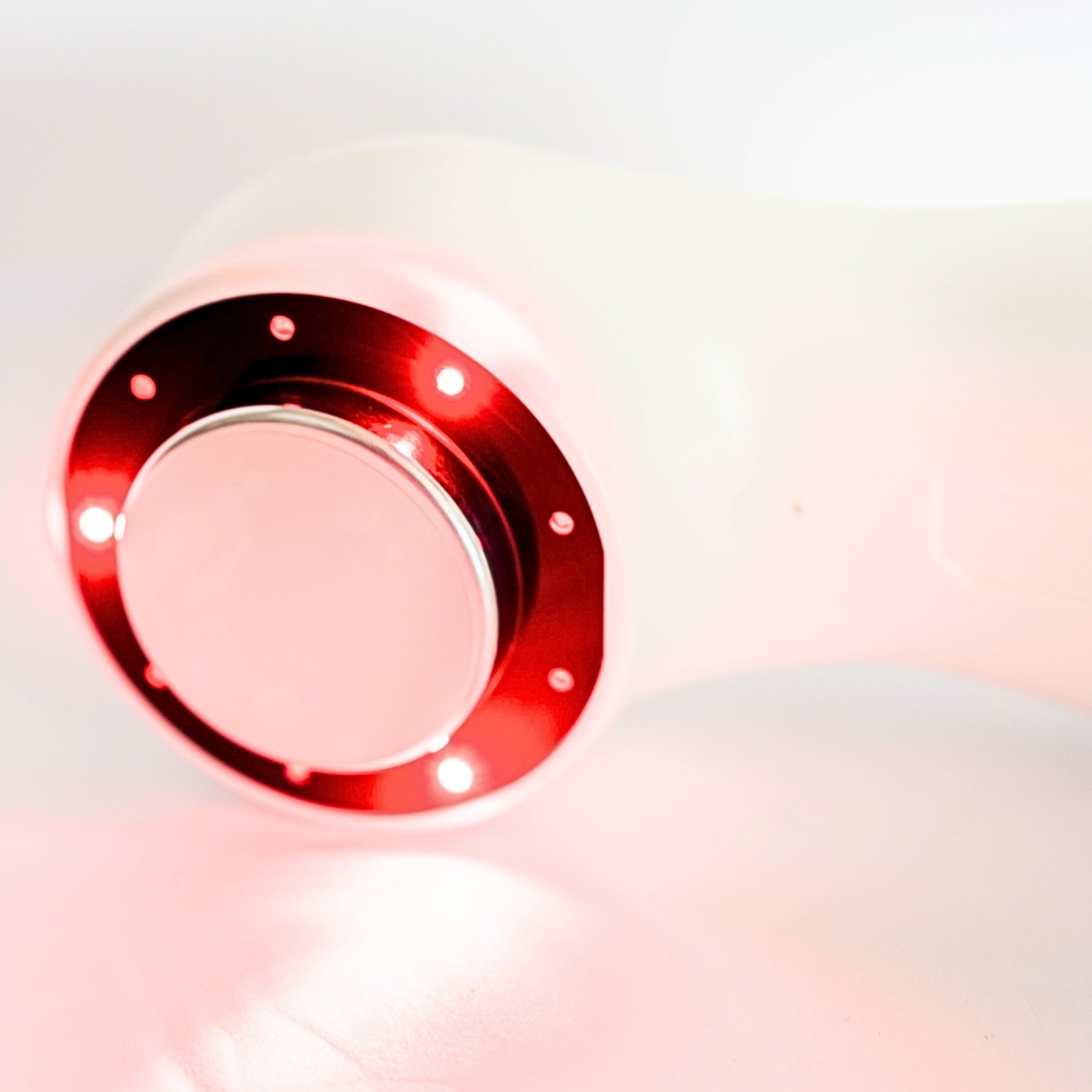 Close-up of Oceanus America Lasonic Dual Therapy Ultrasound device treatment head with red light ring on light background