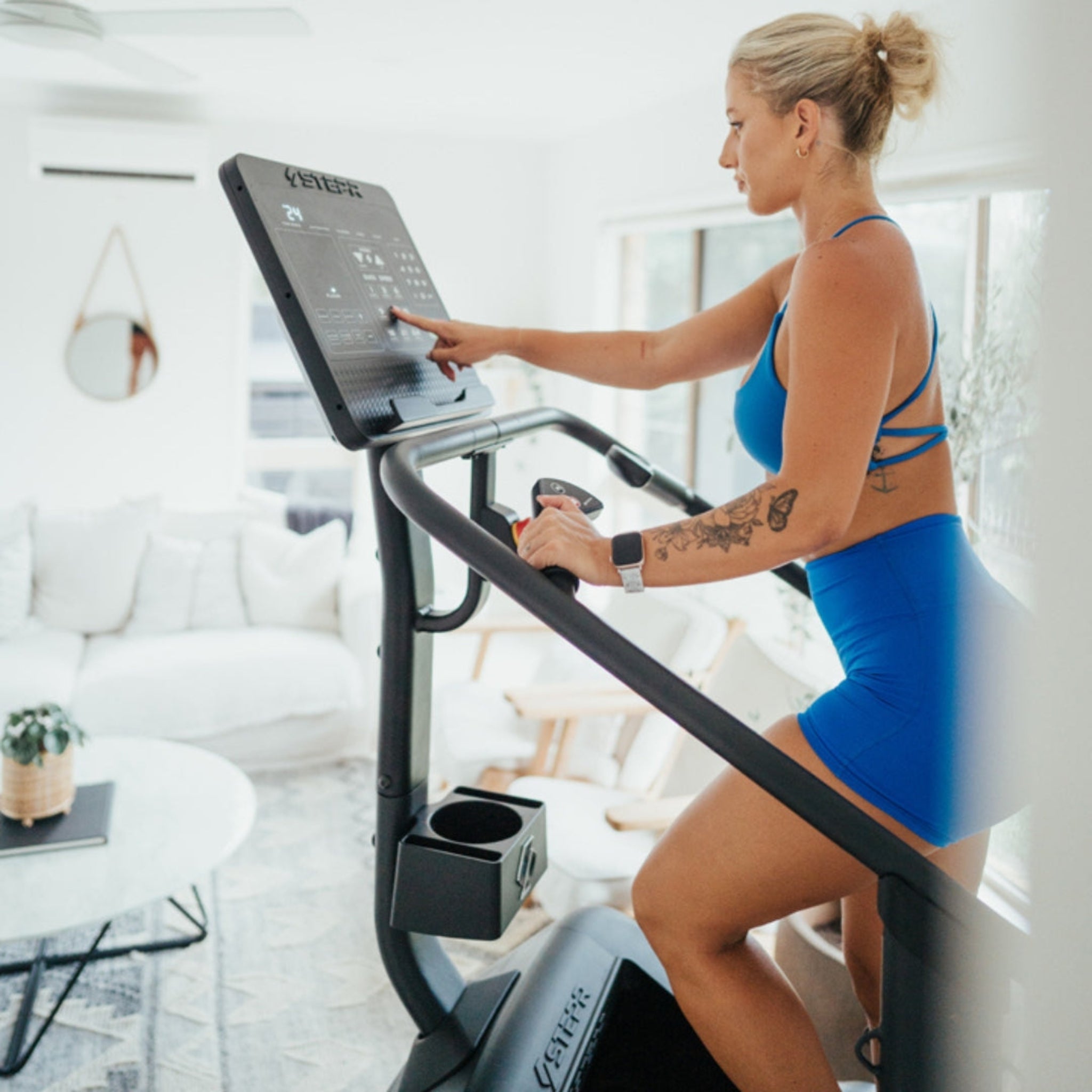 Woman using the STEPR Classic stair climber with LED console in a modern living room for home fitness.