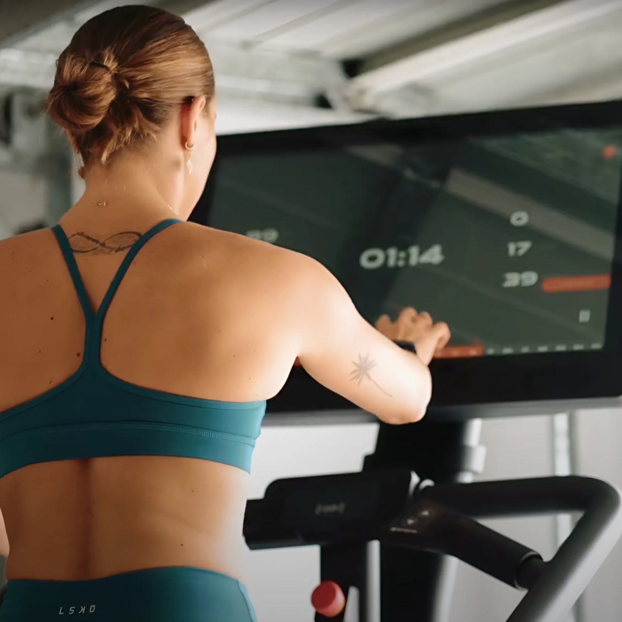 Woman training on the STEPR Pro+ stair climber with 27-inch HD touchscreen console in a modern fitness setting for cardio and strength workouts.