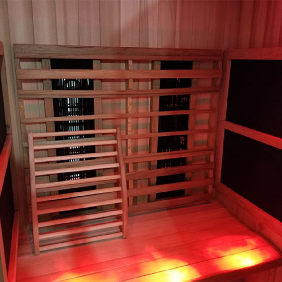 Close-up interior view of the Finnmark FD-2 infrared sauna showing wooden backrests, heating panels behind the backrests, and a red-lit floor