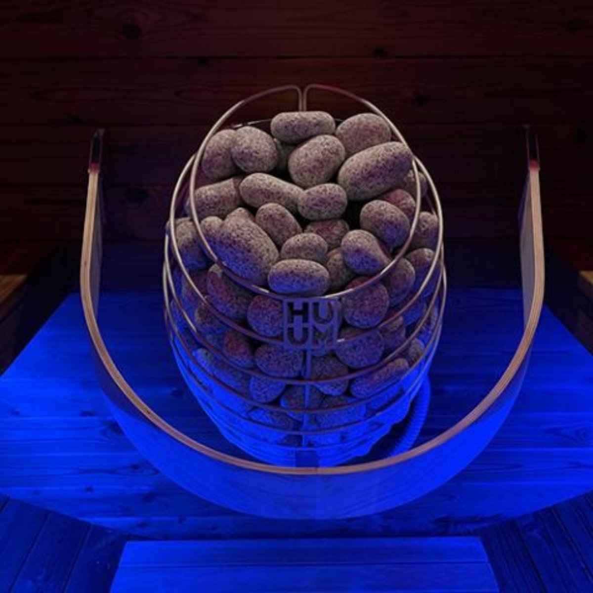 HUUM DROP 9 sauna heater with stone-filled basket under blue lighting