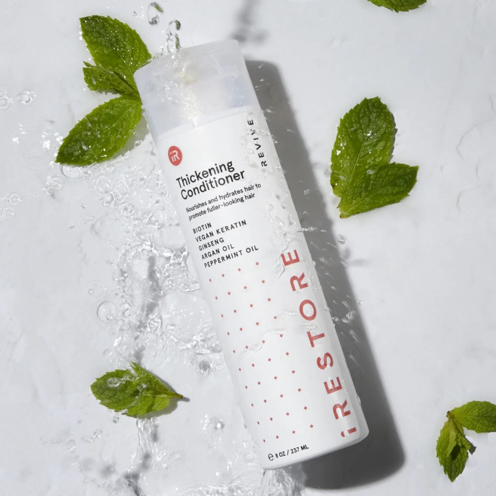 iRestore Thickening Conditioner bottle displayed with fresh mint leaves