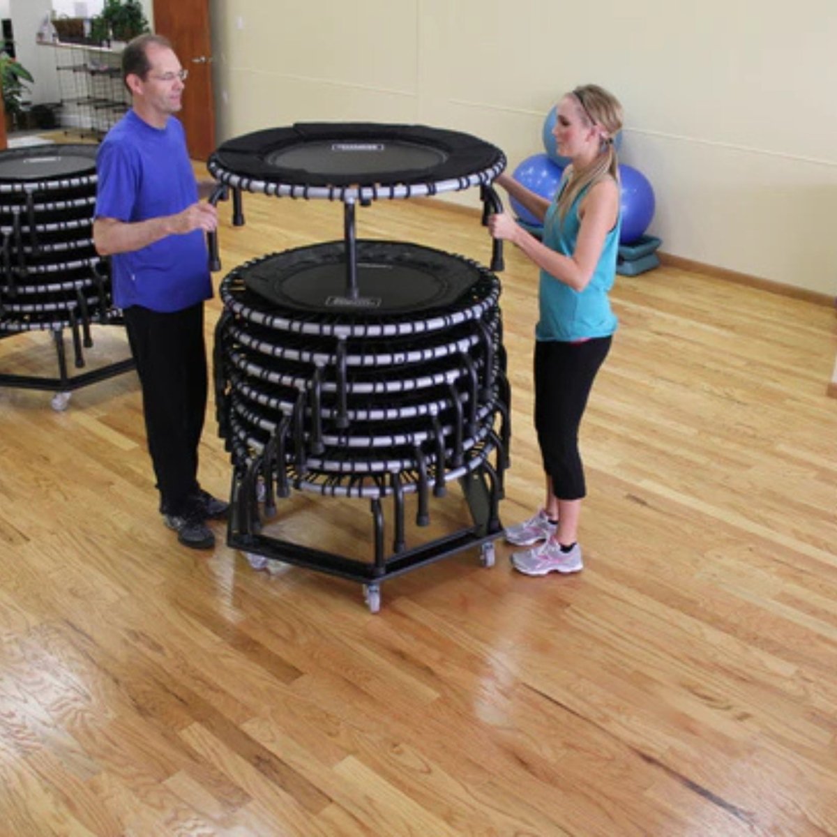 Instructor moving Jumpsport trampoline storage cart in fitness studio