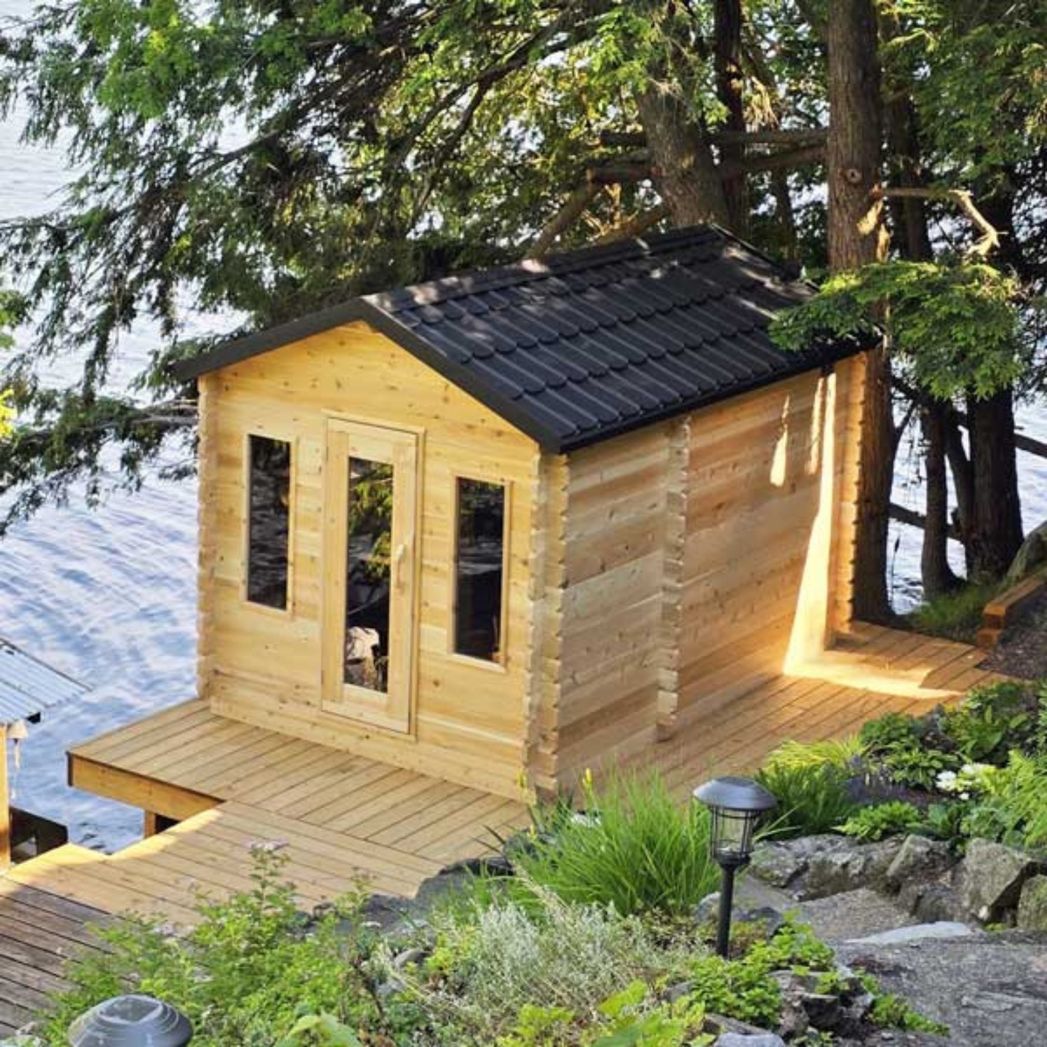 Leisurecraft CT Georgian Cabin Sauna with changeroom, cedar wood design, installed by the lake surrounded by trees.