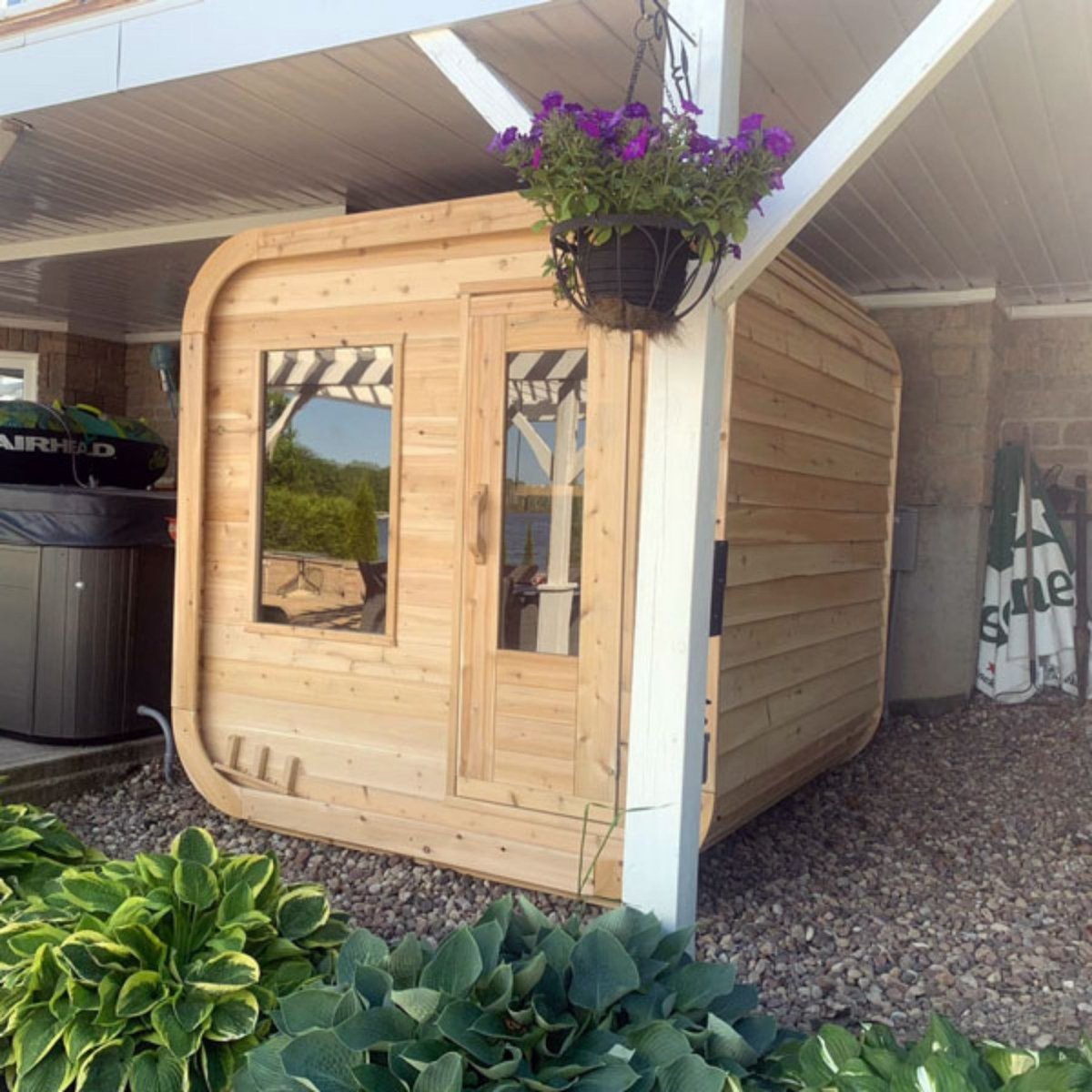 Leisurecraft CT Luna outdoor cedar sauna installed under patio roof surrounded by garden plants.