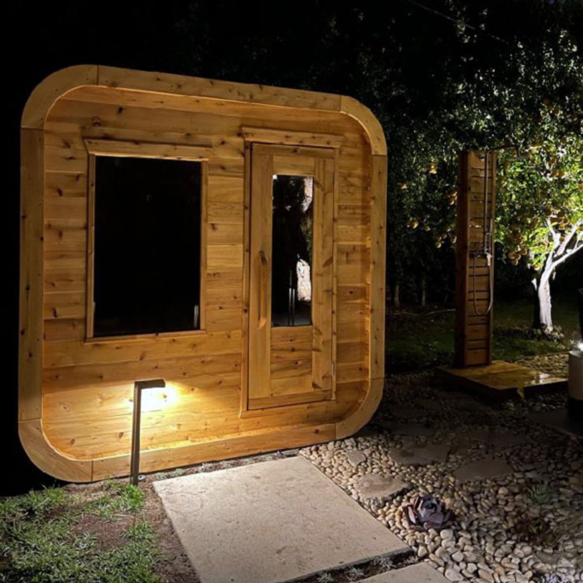 Leisurecraft CT Luna outdoor cedar sauna illuminated at night with modern glass front design.