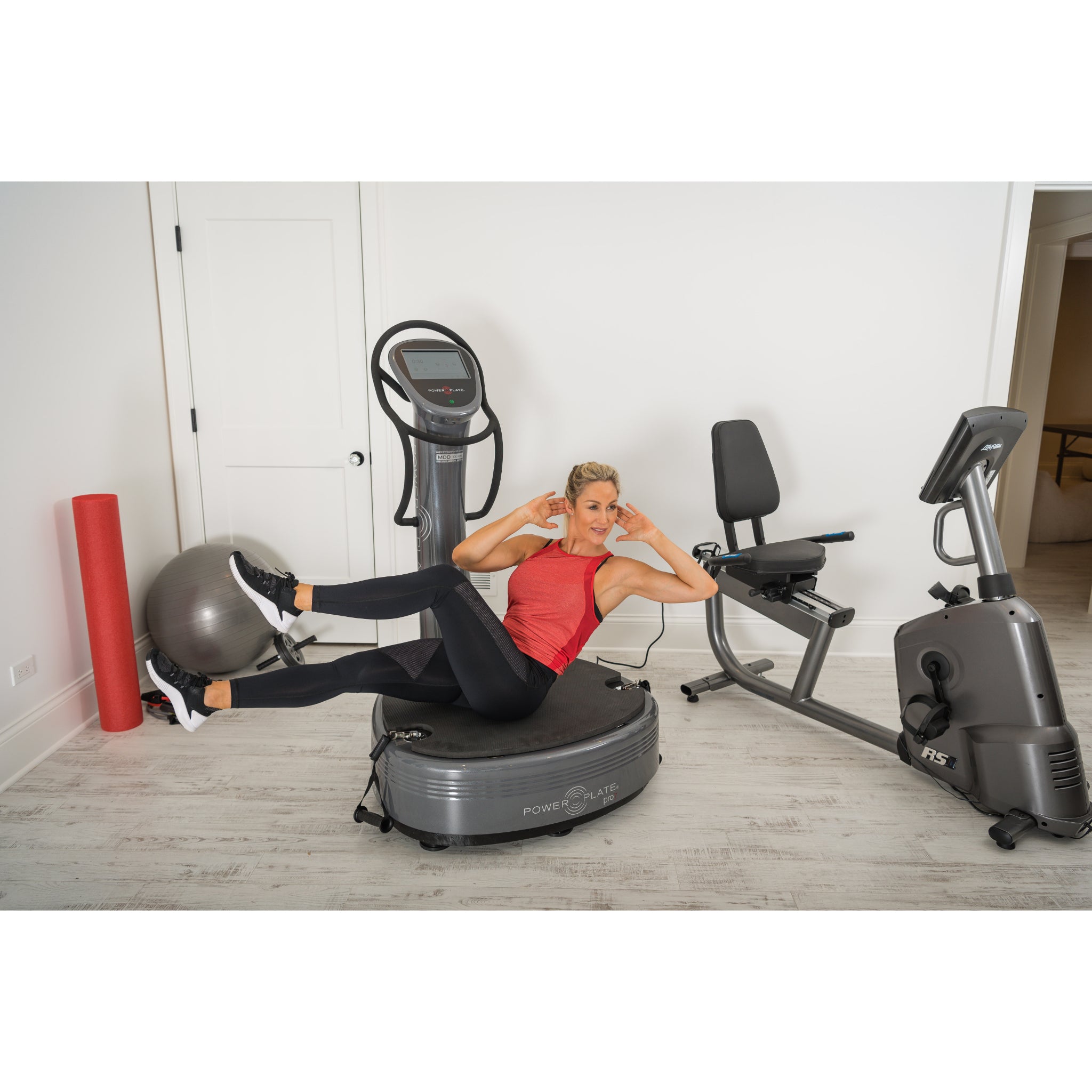 Woman performing a core exercise on the Power Plate pro7 vibration training machine in a home gym setting