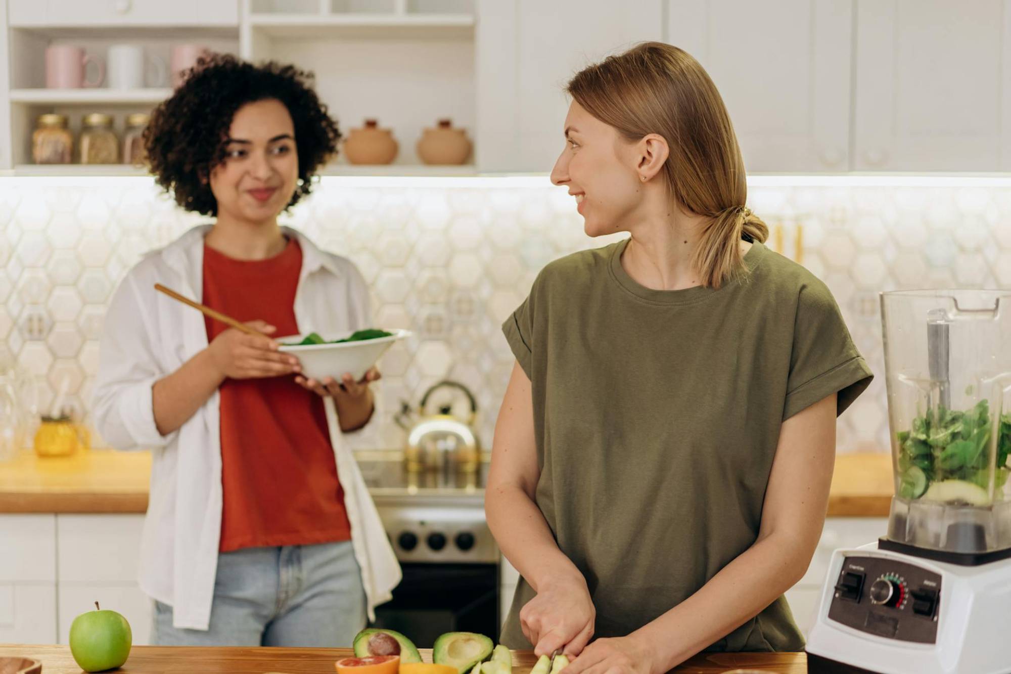 two women looking at each other while preparing healthy food which shows great gut health