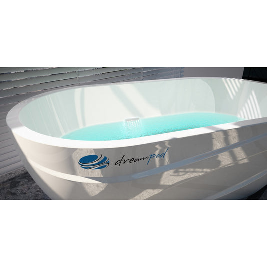 Dreampod ice bath with sleek white exterior, filled with clear blue water, placed outdoors near a wall