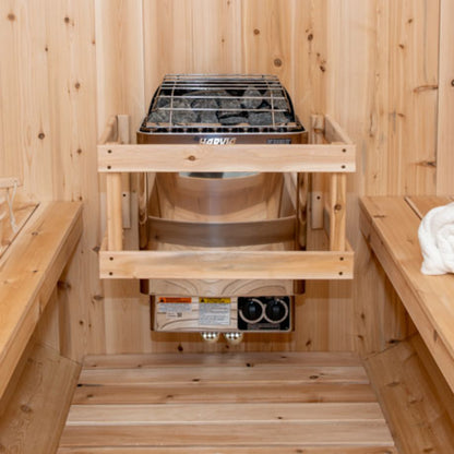 Close-up of Harvia 8kW sauna heater with stones installed inside a wooden barrel sauna, framed by cedar benches