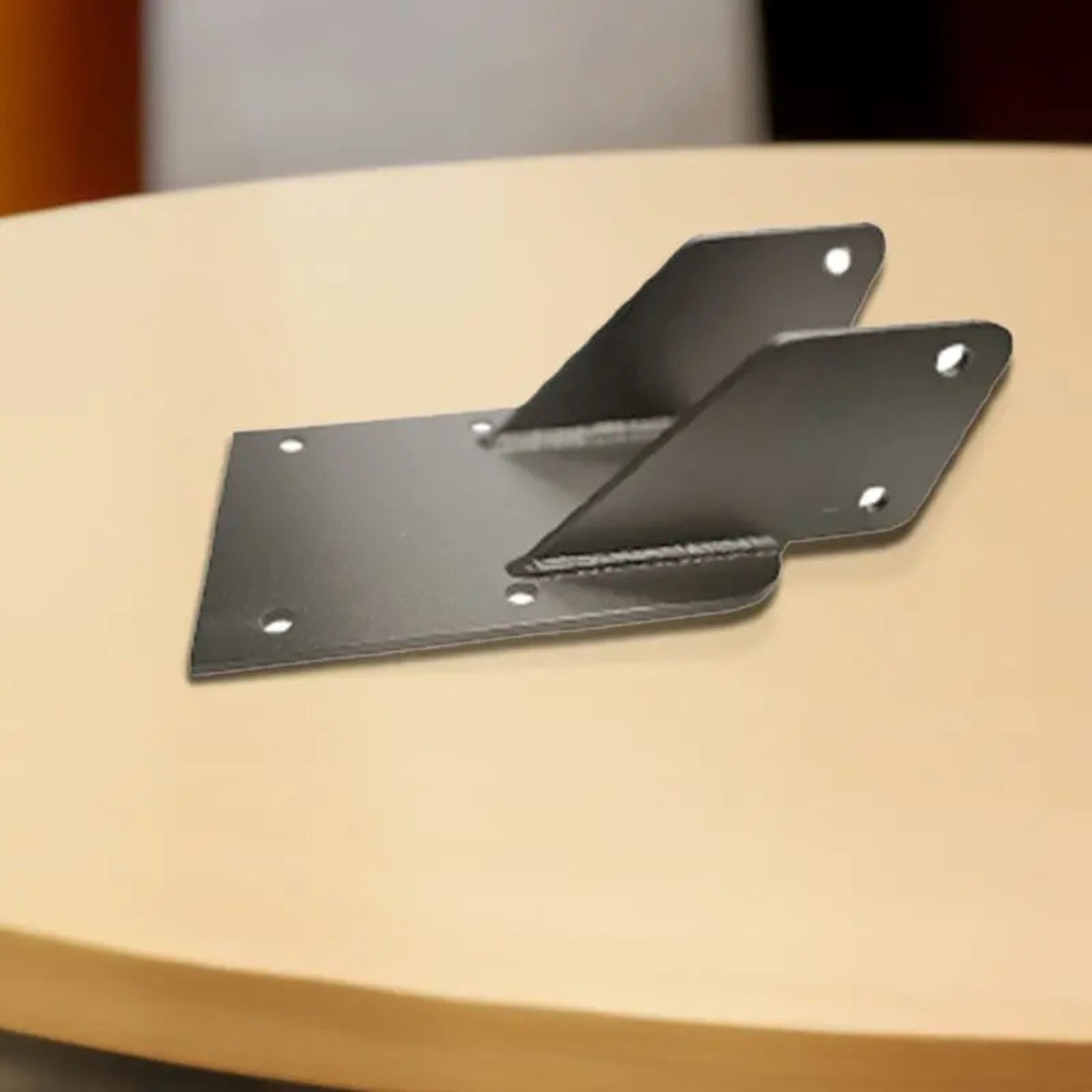 VersaClimber H/HP wall mount installation brackets in black steel finish, displayed on a wooden surface for secure assembly and mounting guidance