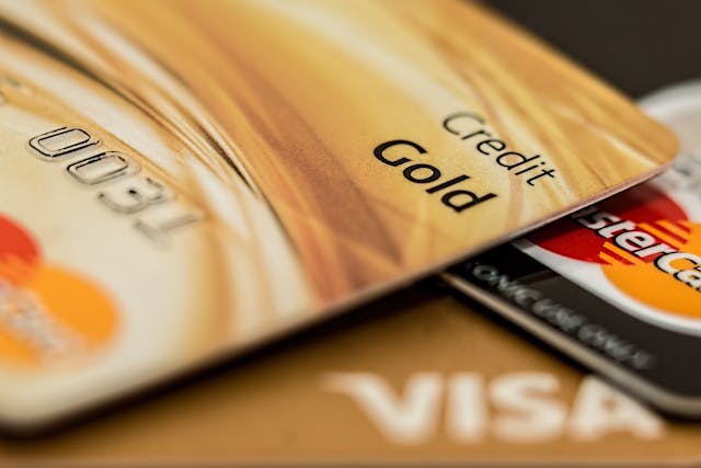 Close-up of a Visa card, MasterCard card, and a gold credit card on a blurred background.
