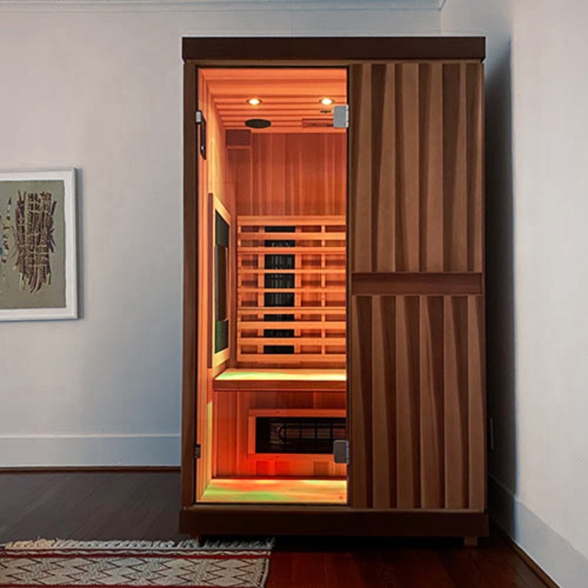 Front view of the Finnmark FD-2 infrared sauna installed in a modern indoor room with illuminated interior heater panels visible through the closed glass door.