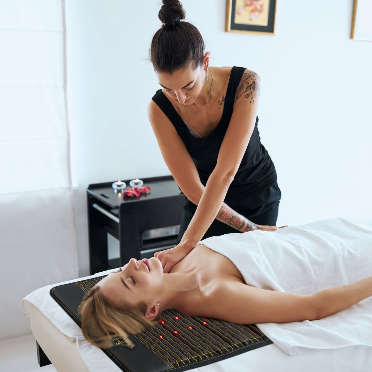 Woman receiving a massage while lying on a PEMF infrared heating mat with red light therapy for deep relaxation