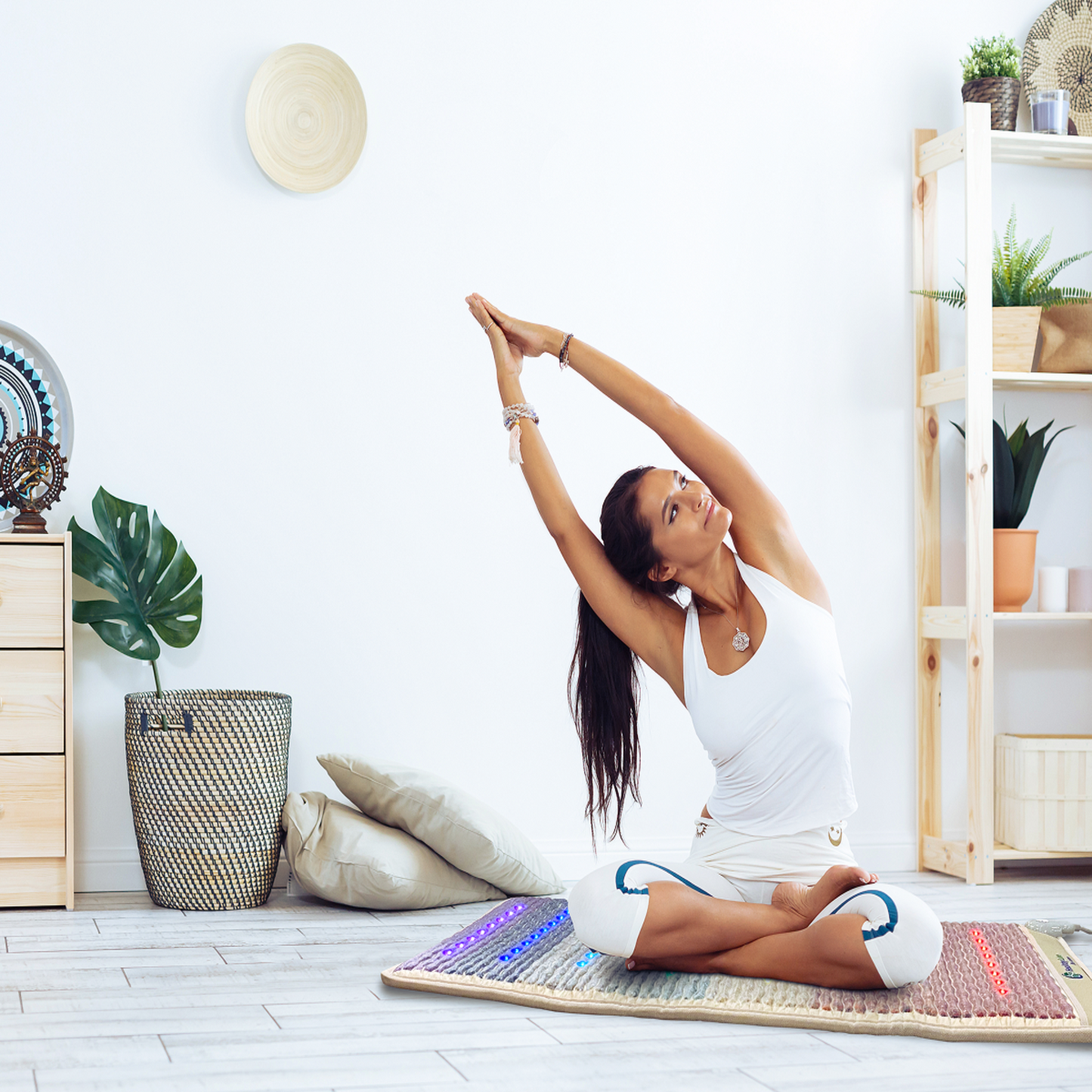 Woman practicing yoga on HealthyLine Rainbow Chakra Mat 7428 with PEMF, Far Infrared, and chakra gemstone therapy lights