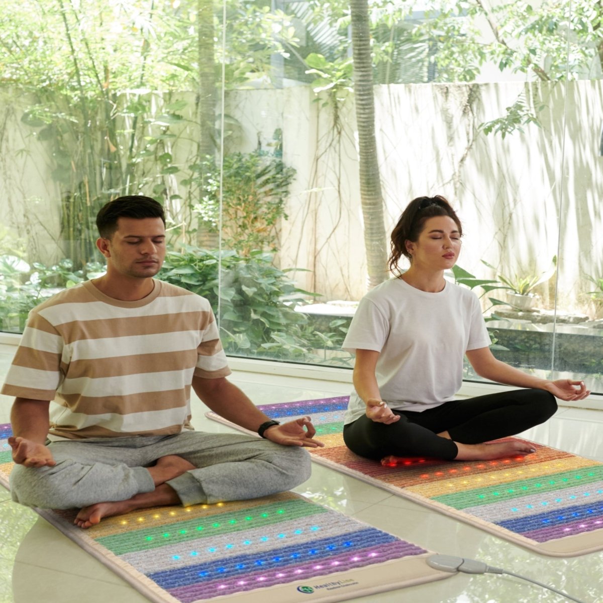 Two people meditating on HealthyLine Rainbow Chakra Mat 7428 with PEMF, Far Infrared, and chakra gemstone therapy