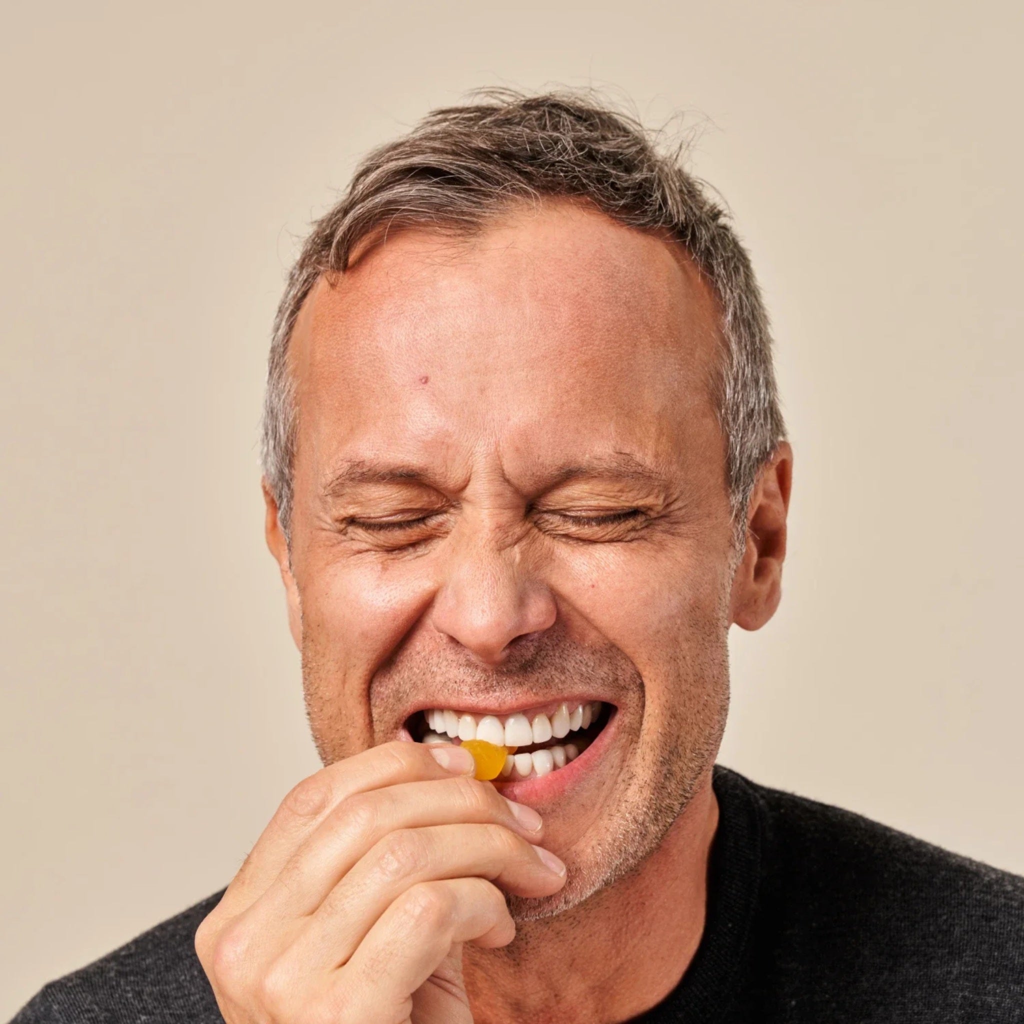 Smiling man eating iRestore Biotin Gummy for healthy hair support