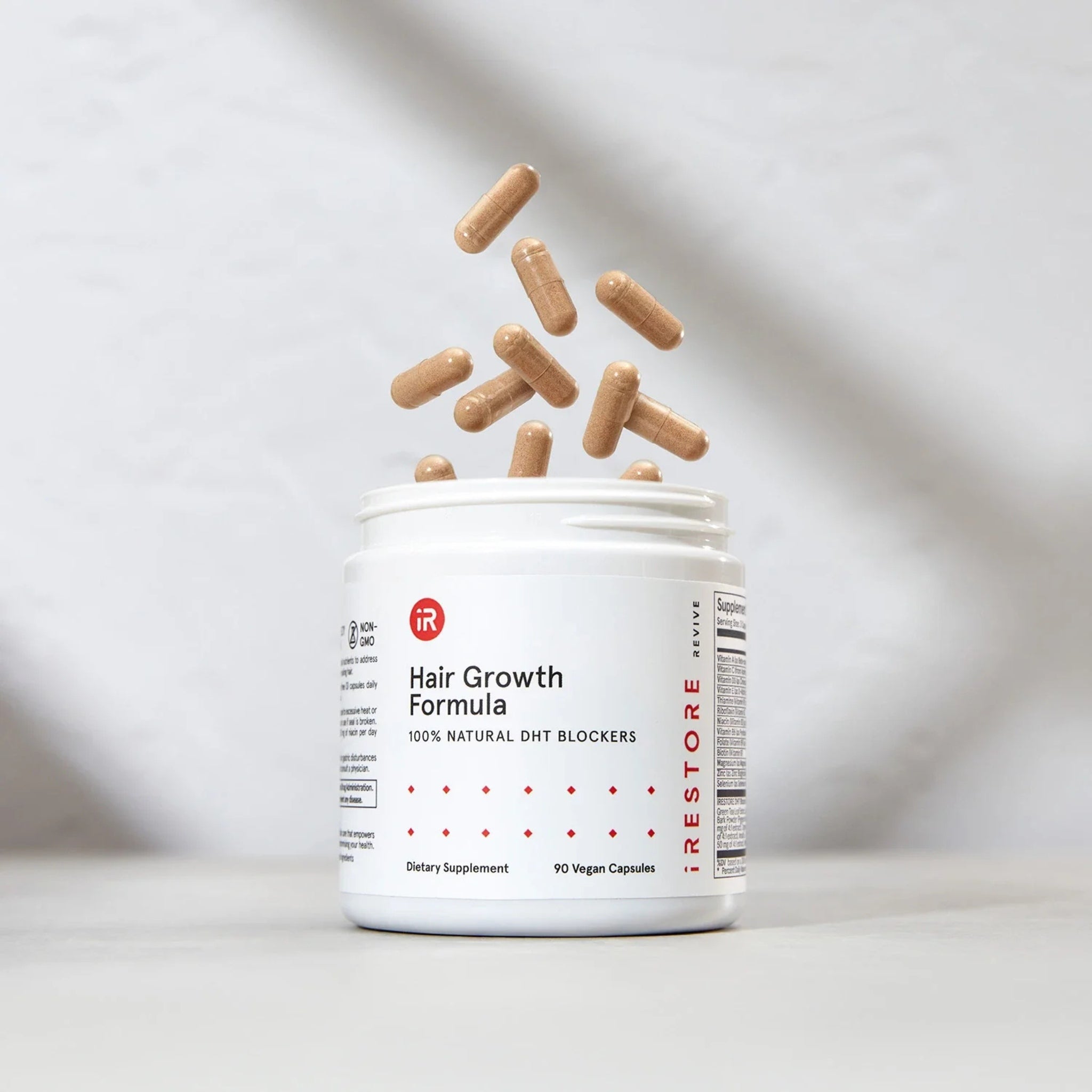 Open jar of iRestore Hair Growth Formula with capsules spilling out