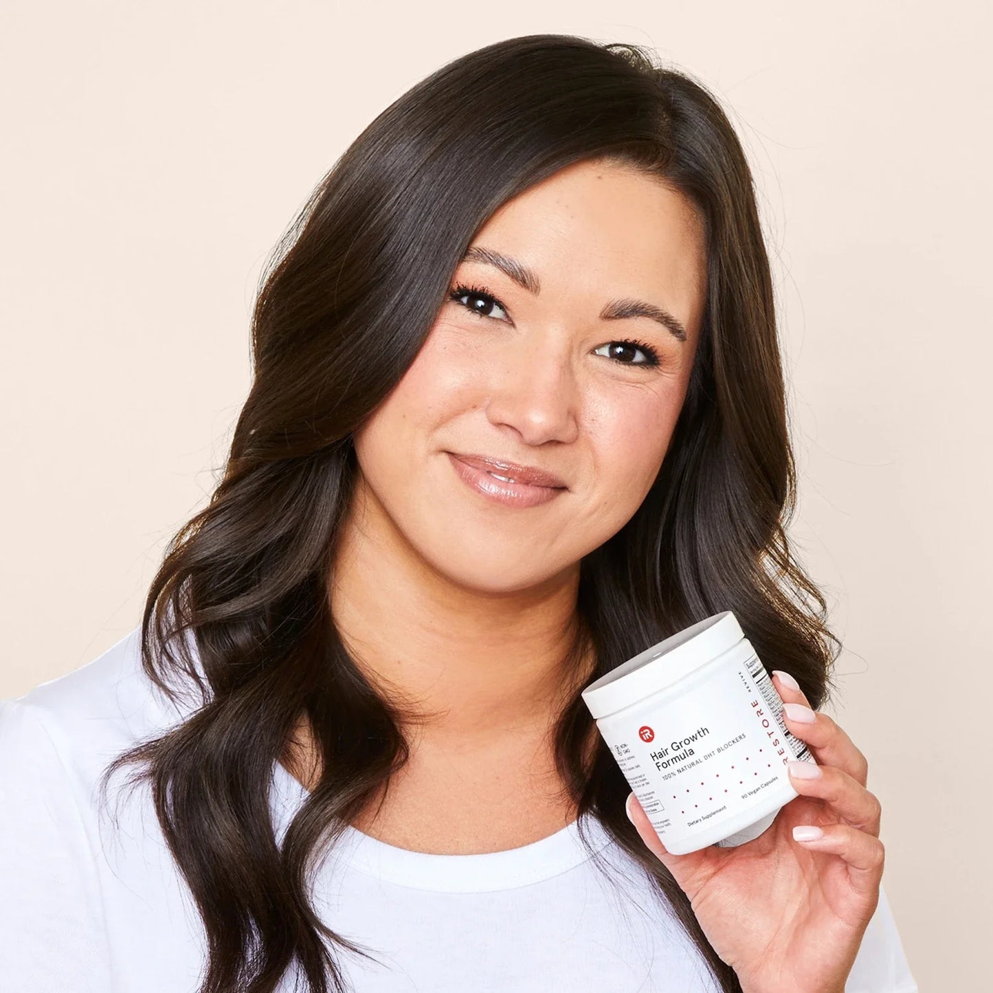 Smiling woman holding iRestore Hair Growth Formula bottle in hand