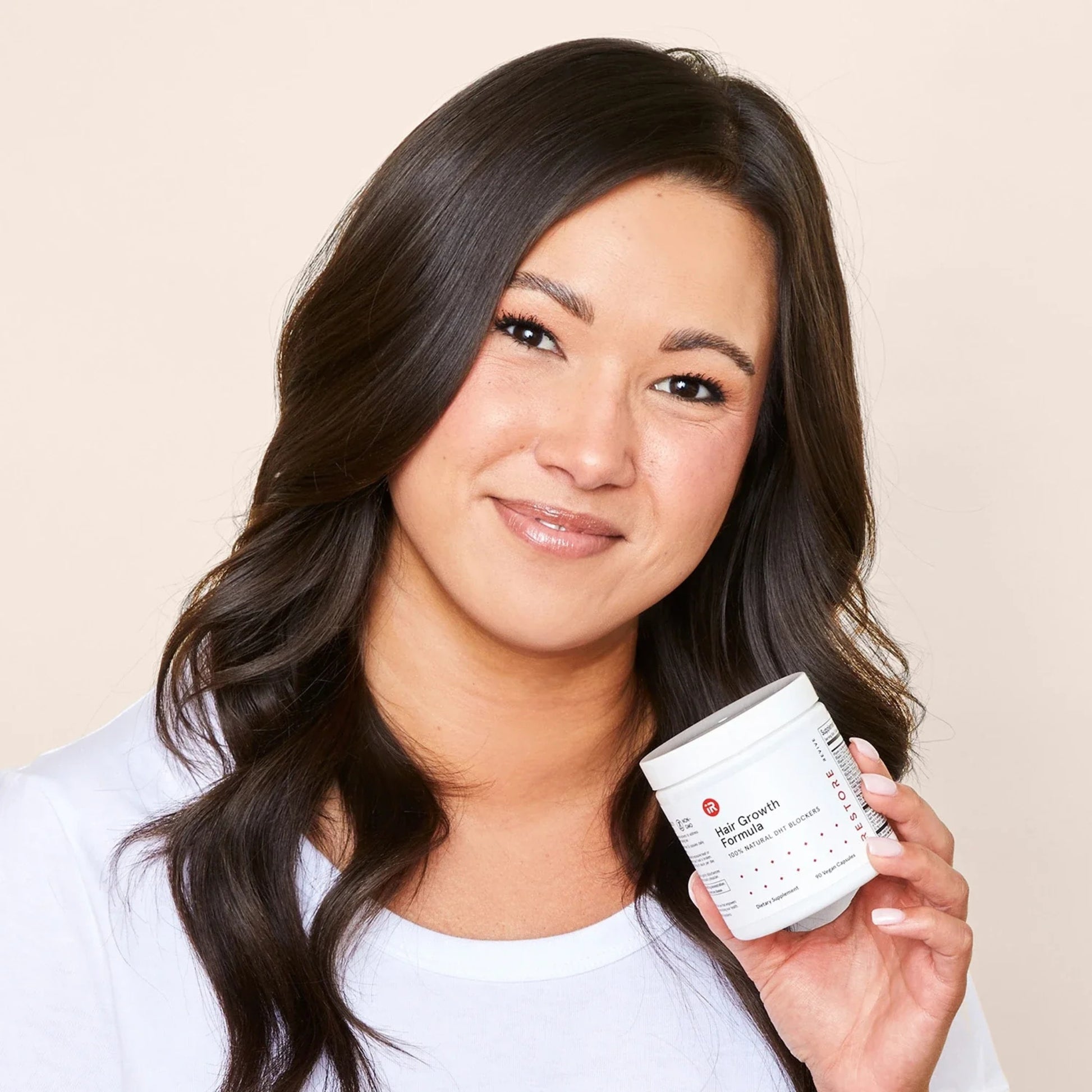 Smiling woman holding iRestore Hair Growth Formula bottle in hand