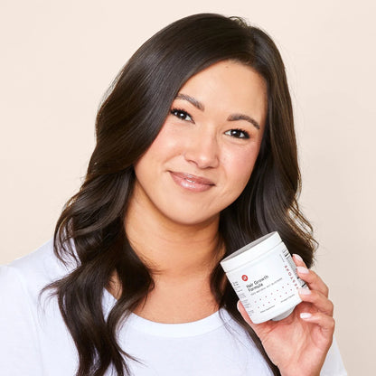 Smiling woman holding iRestore Hair Growth Formula bottle in hand