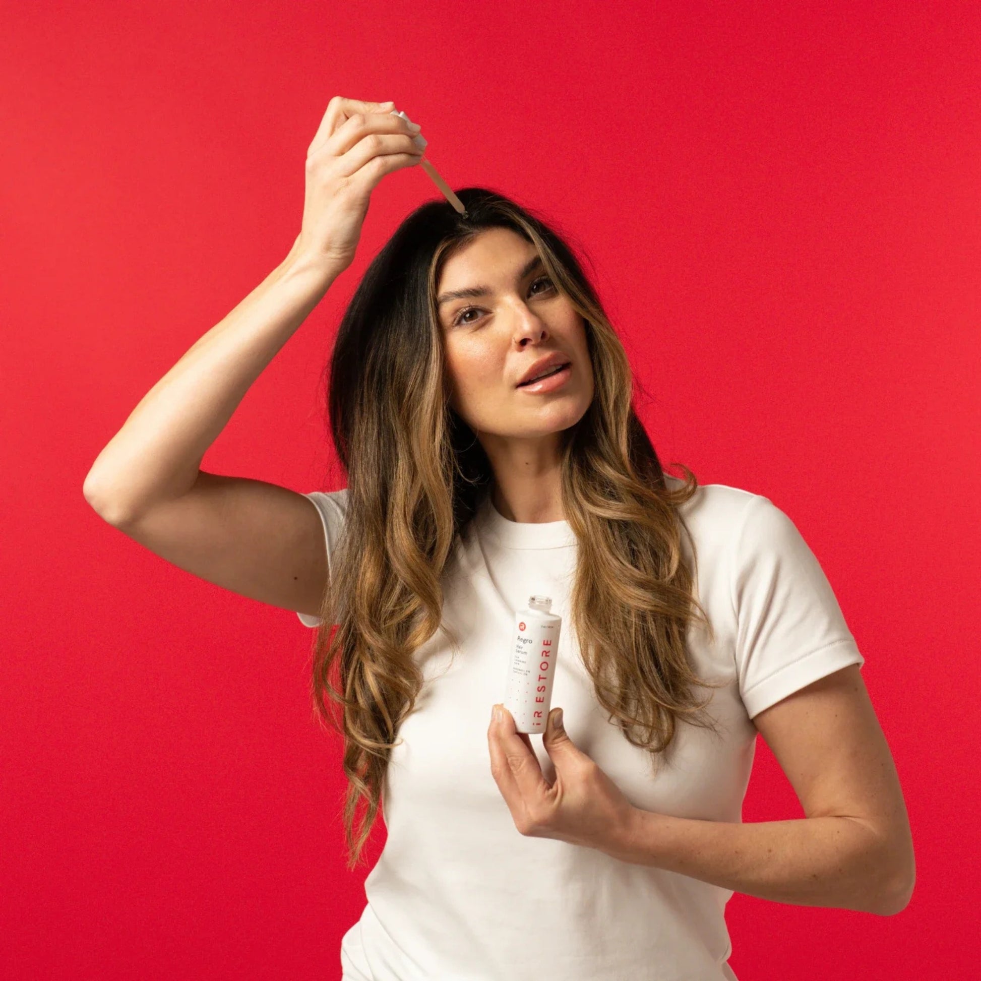 Woman applying iRestore 3-in-1 Hair Growth Serum for stronger fuller hair