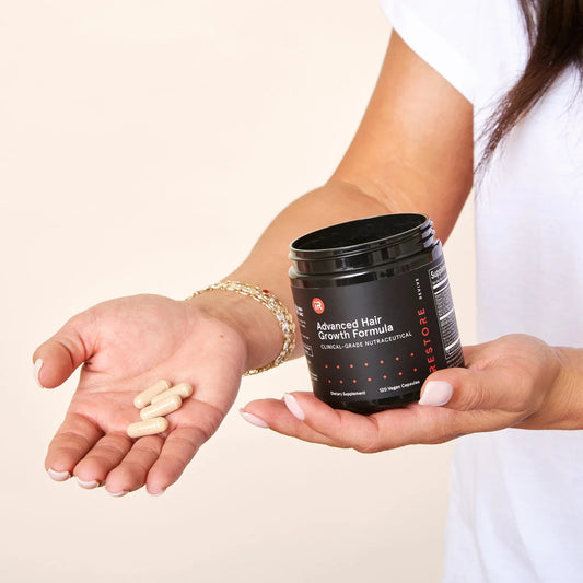 Person holding iRestore Revive Advanced Hair Growth Formula supplement bottle