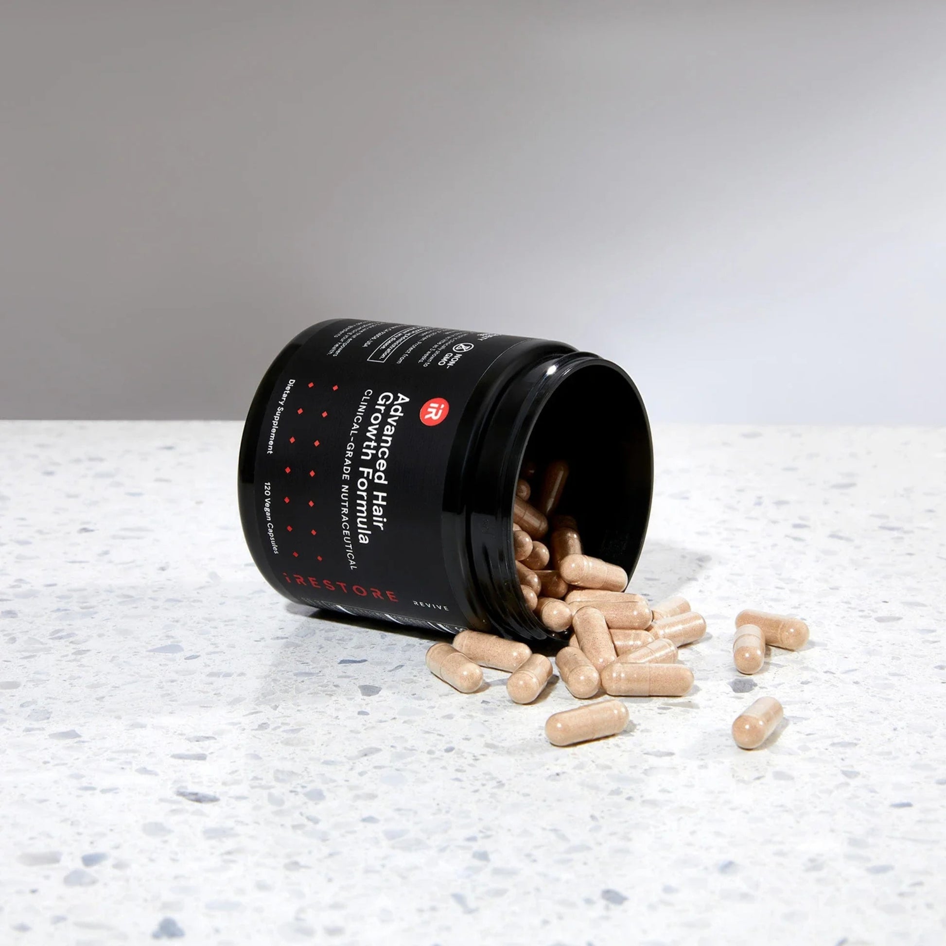 Open jar of iRestore Revive Advanced Hair Growth Formula showing capsules