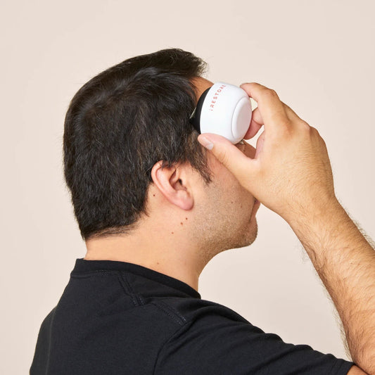 Man using iRestore scalp massager to promote healthy hair and relaxation