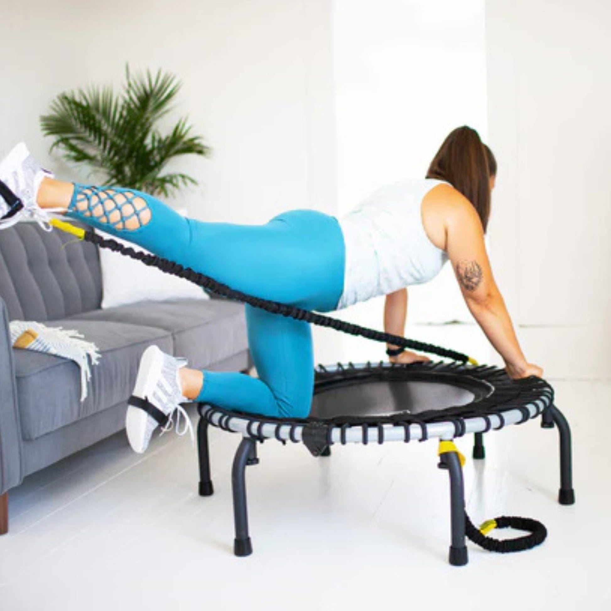 Woman training in home gym with Jumpsport trampoline resistance cords