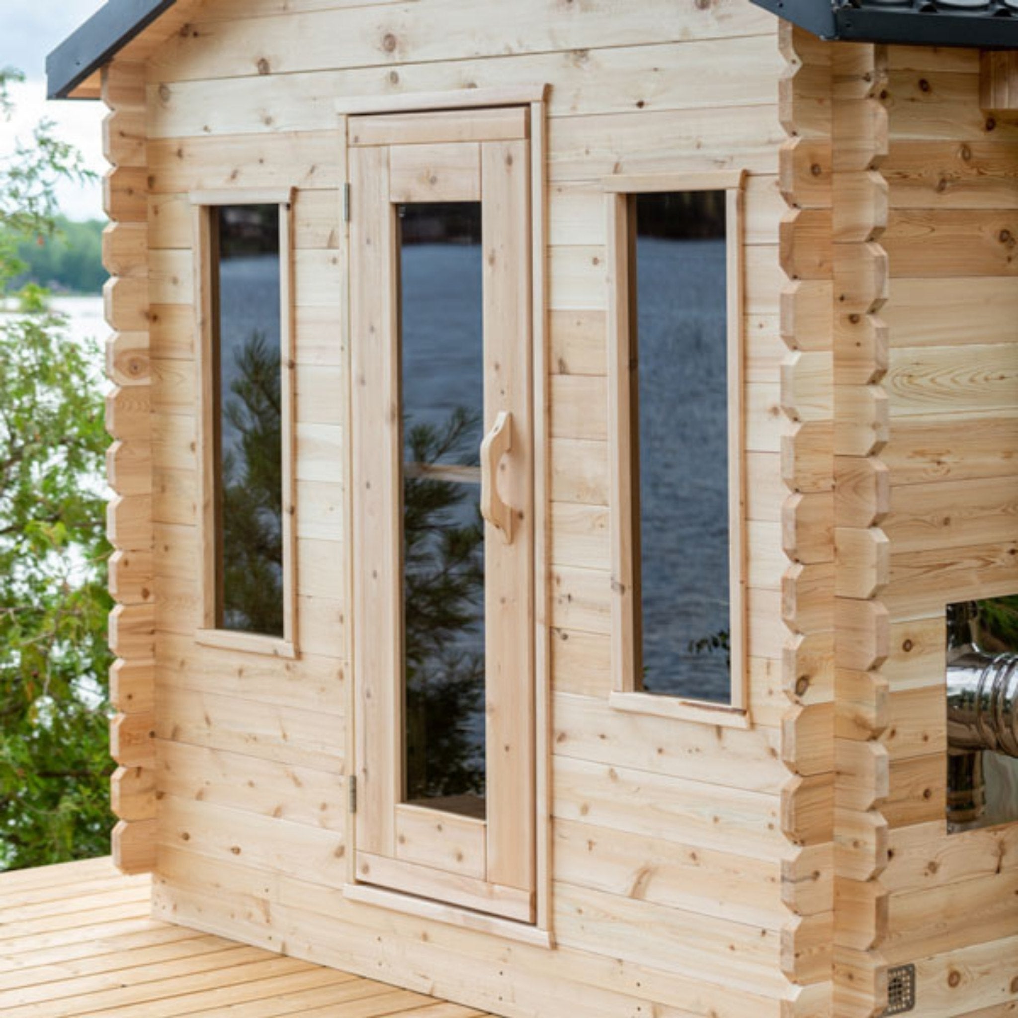 Leisurecraft CT Georgian Cabin Sauna front view with cedar-framed glass door and tall windows overlooking the water and trees.