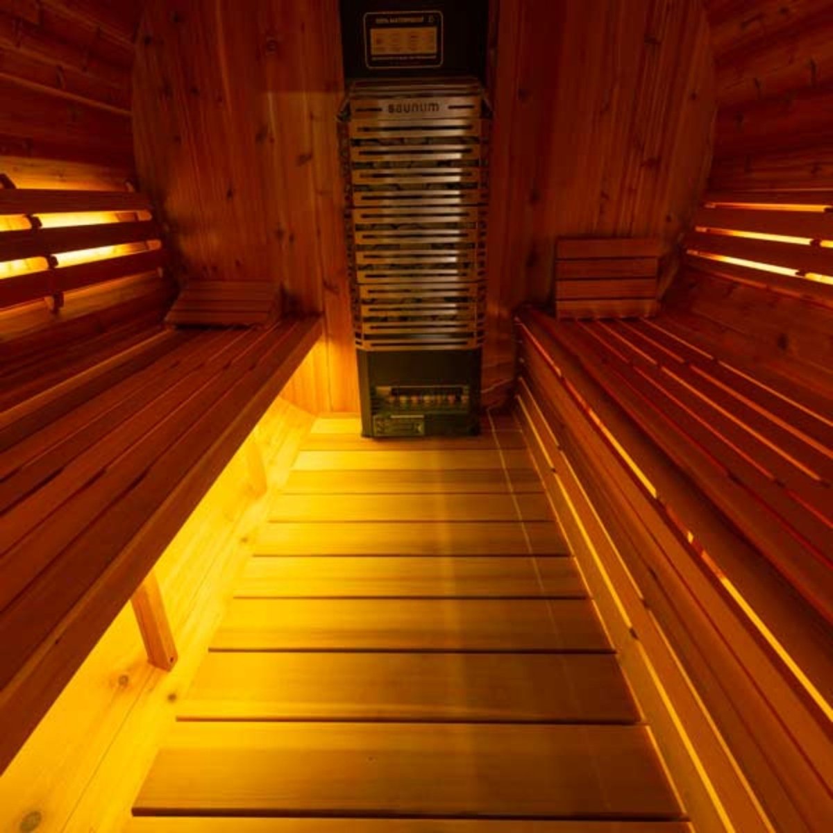 Leisurecraft double bench set inside sauna with warm amber lighting highlighting tiered cedar seating