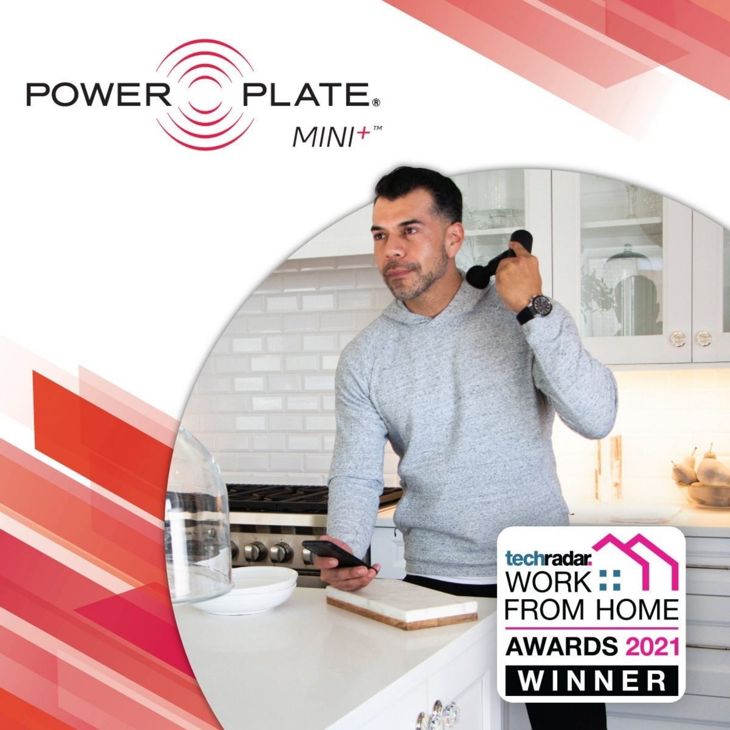 Man using Power Plate Mini+ massage gun on shoulder in kitchen setting

