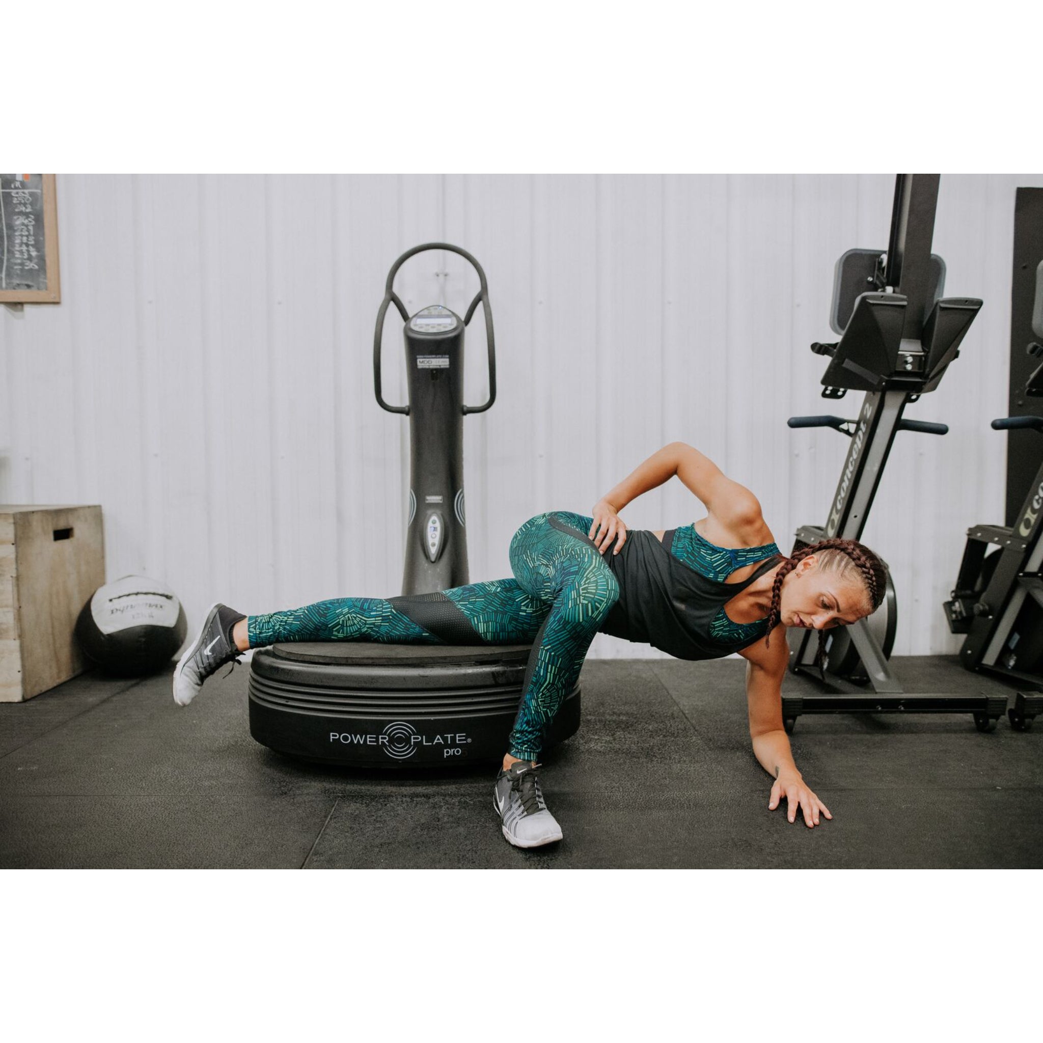 Woman performing a side plank exercise on the Power Plate pro5 vibration training machine in a gym setting