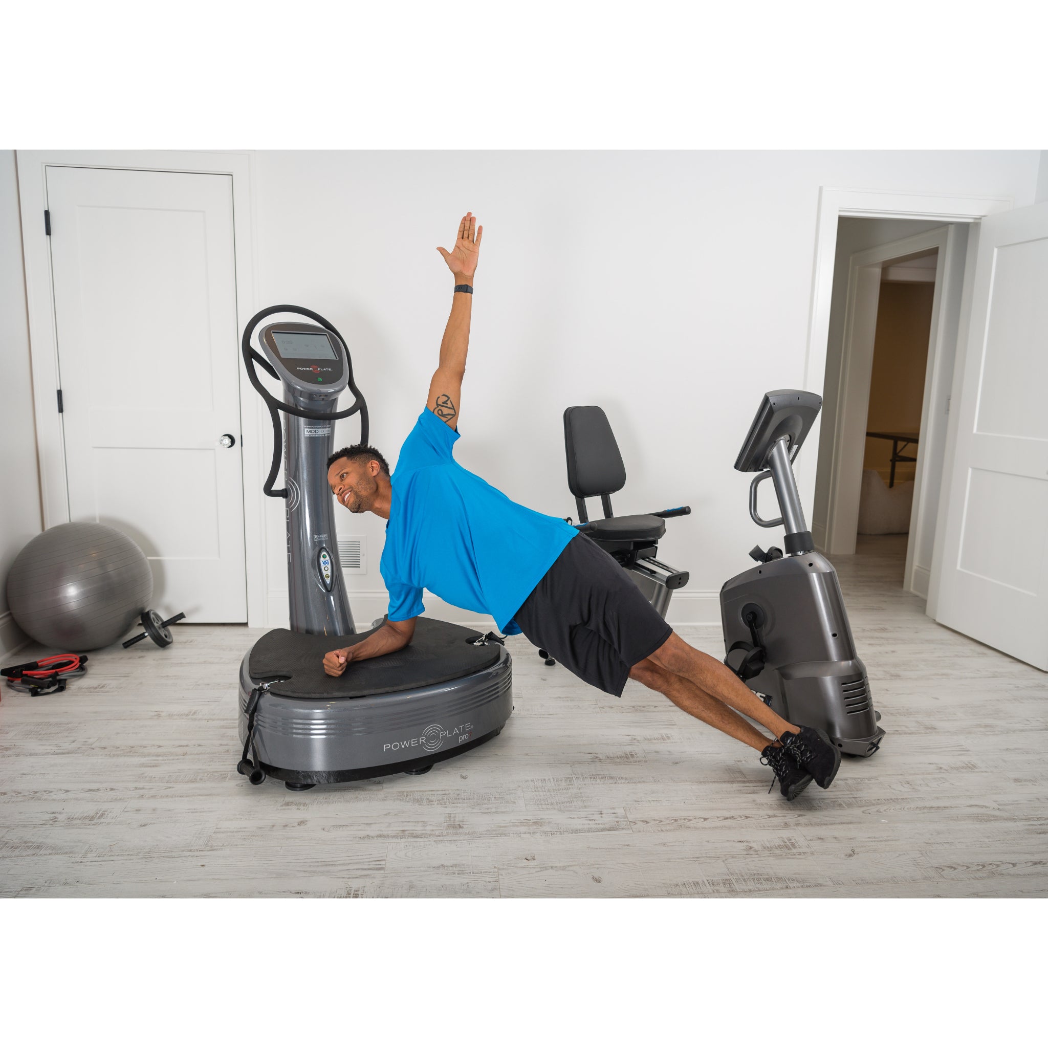 Man performing a side plank exercise on the Power Plate pro7 vibration training machine in a home gym setting
