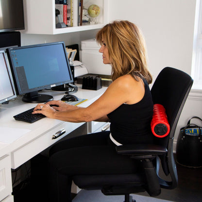 Woman performing upper back stretch with Power Plate vibrating foam roller on gym floor