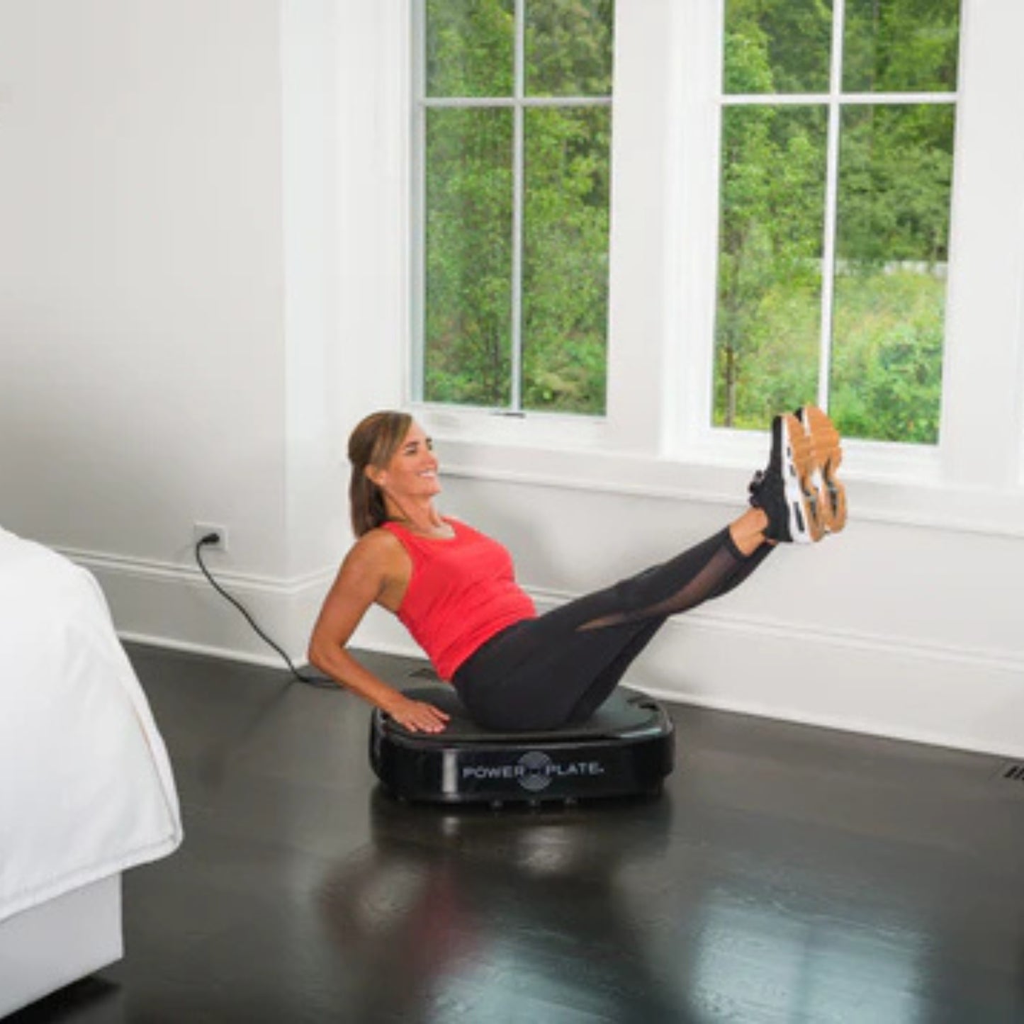 Man performing leg workout on Power Plate vibration platform at home