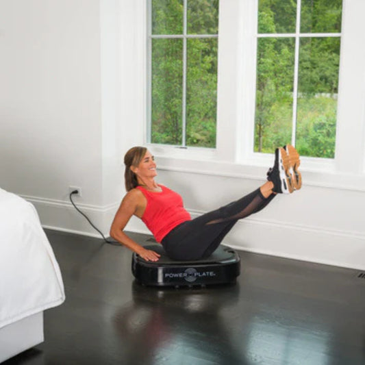 Man performing leg workout on Power Plate vibration platform at home