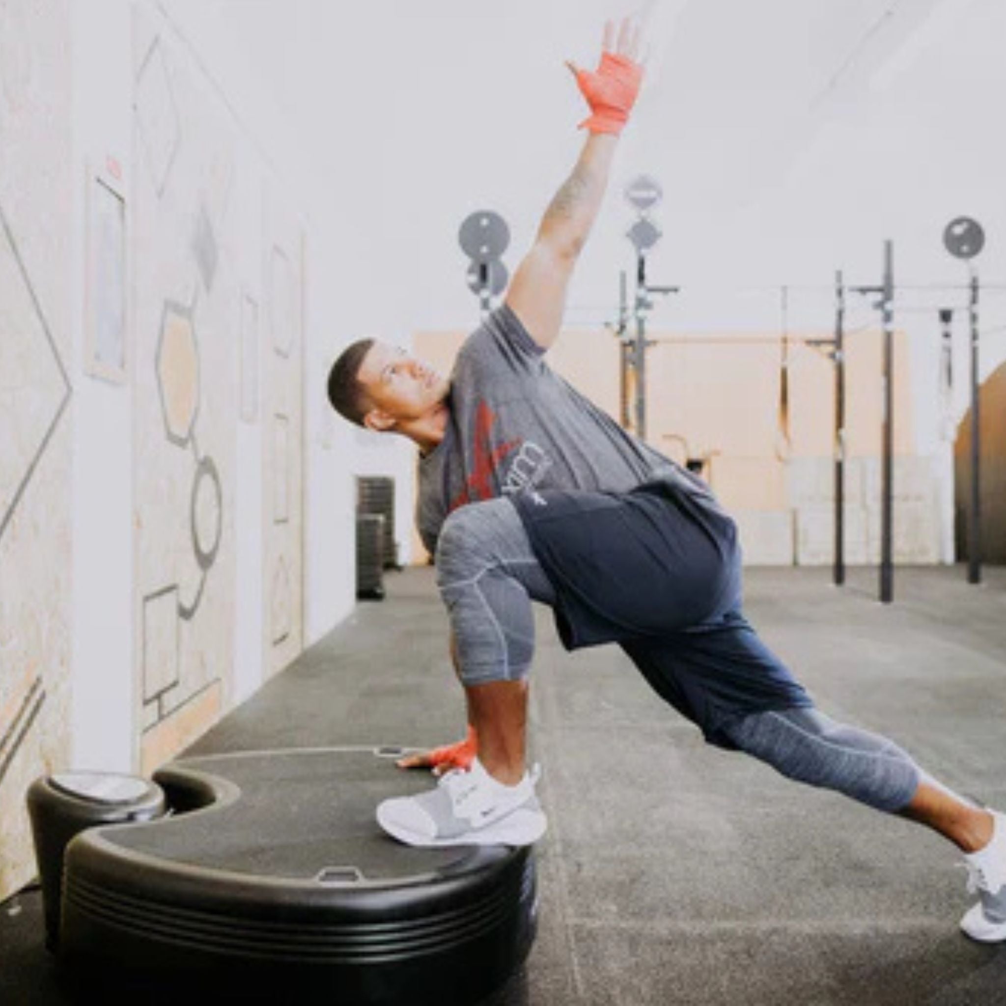 Athlete performing side lunge exercise on Power Plate Pro vibration platform outdoors