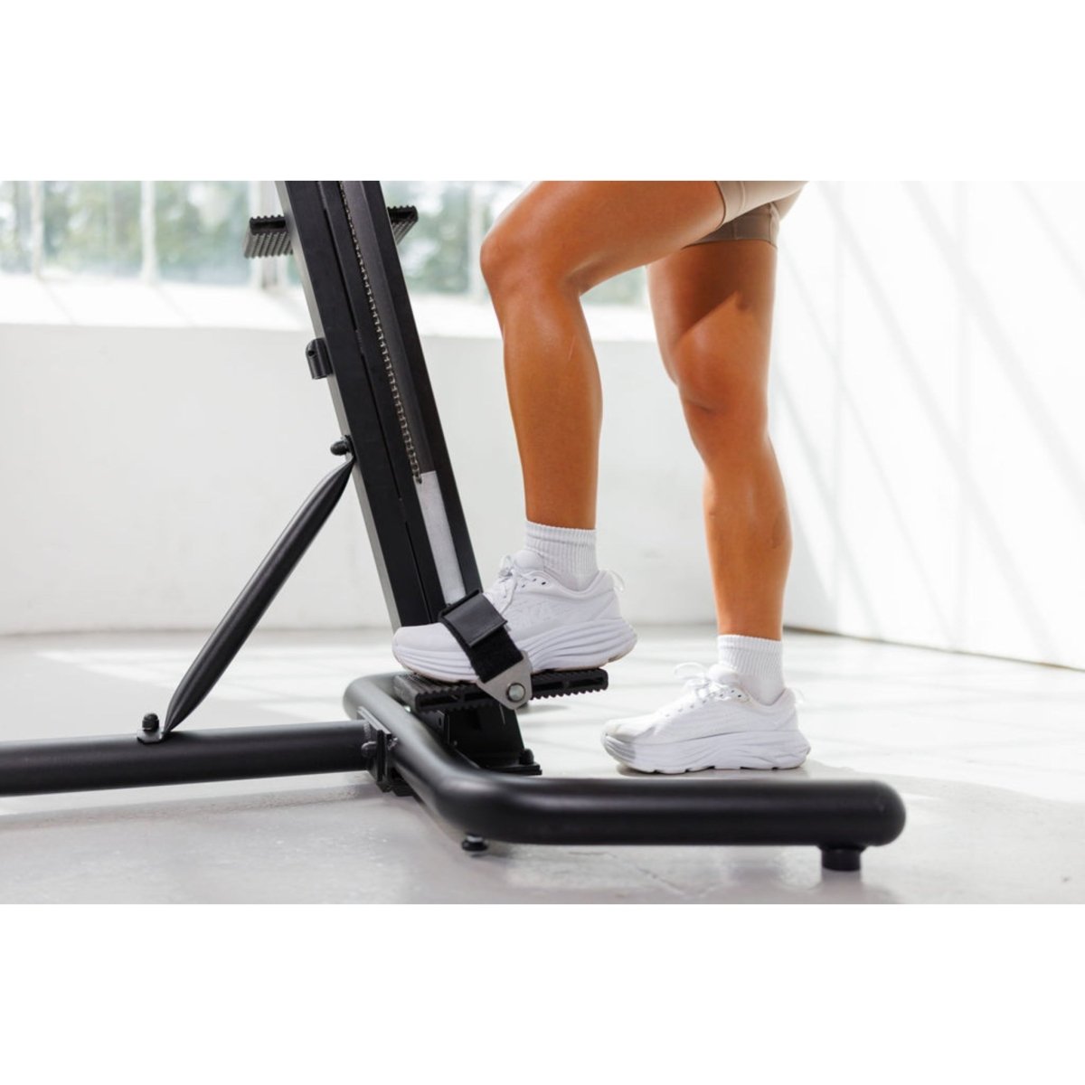 Close-up of a woman’s legs using the VersaClimber TS-M Magnetic in regular black, highlighting full-body zero-impact cardio and strength training in a modern studio setting.